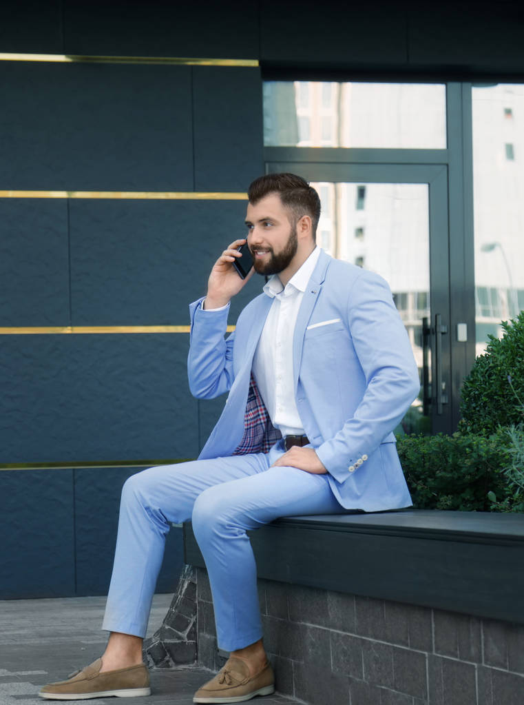 Knappe succesvolle zakenman praten op mobiele telefoon buitenshuis - Foto, afbeelding