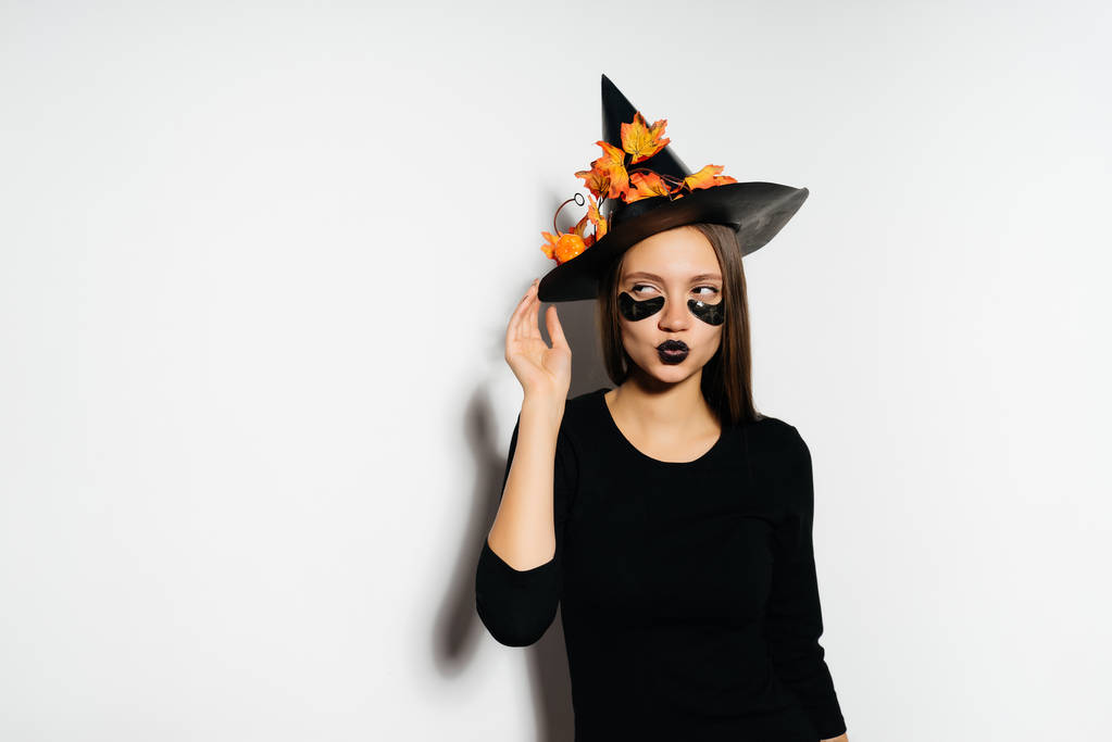 nuori seksikäs goottilainen tyttö juhlii halloween, pukeutunut noita, täysin mustat vaatteet, hymyillen
 - Valokuva, kuva