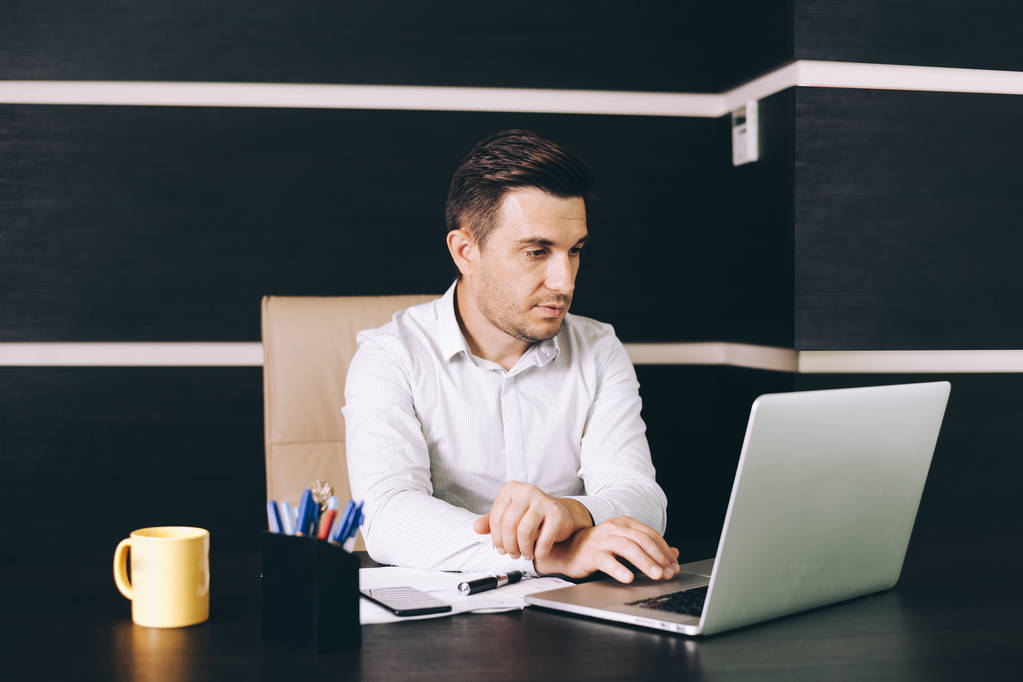 Homme d'affaires attrayant en tenue décontractée intelligente assis à son lieu de travail au bureau
 - Photo, image
