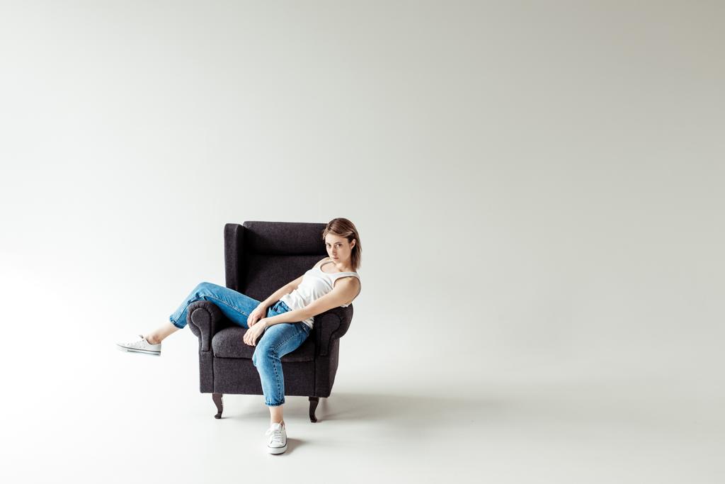vrouw in singlet zittend op fauteuil  - Foto, afbeelding