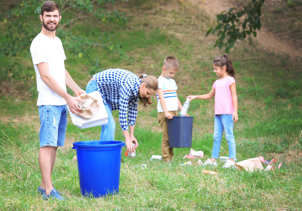 Perhe kerää roskia ulkona. Kierrätyksen käsite
 - Valokuva, kuva