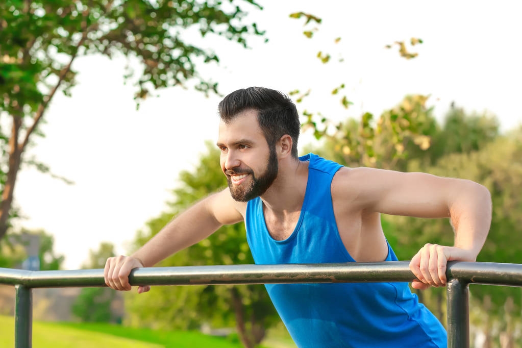 Handsome young man exercising in park - Photo, Image
