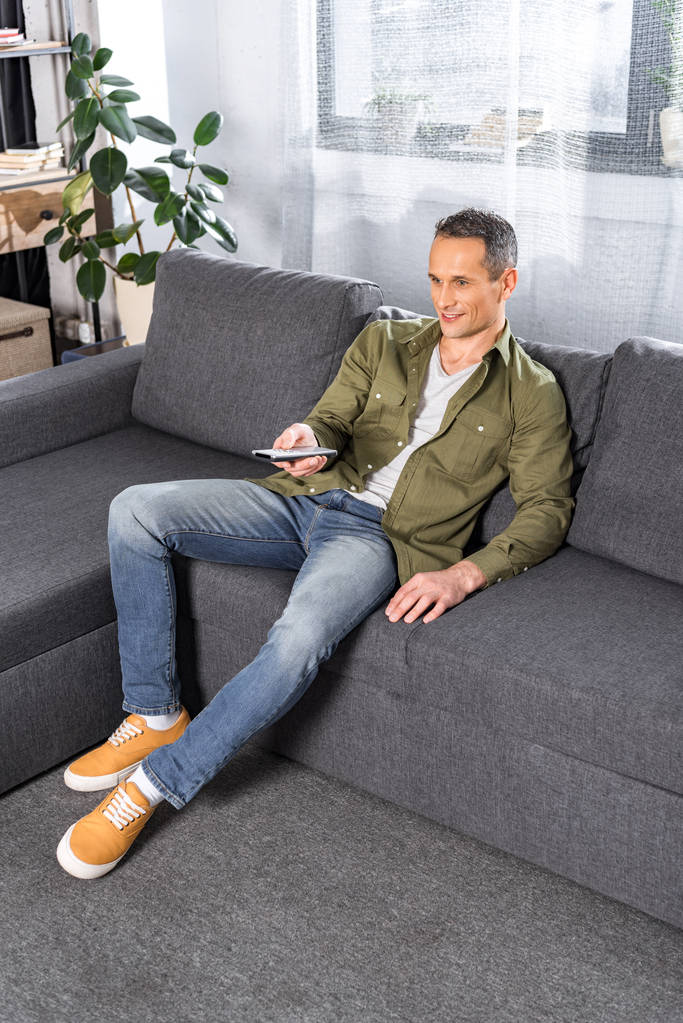 Человек с телевизором сидит на диване
 - Фото, изображение