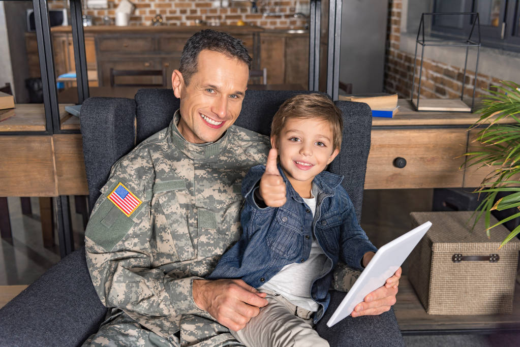 vader in militair uniform en zoon met tablet - Foto, afbeelding