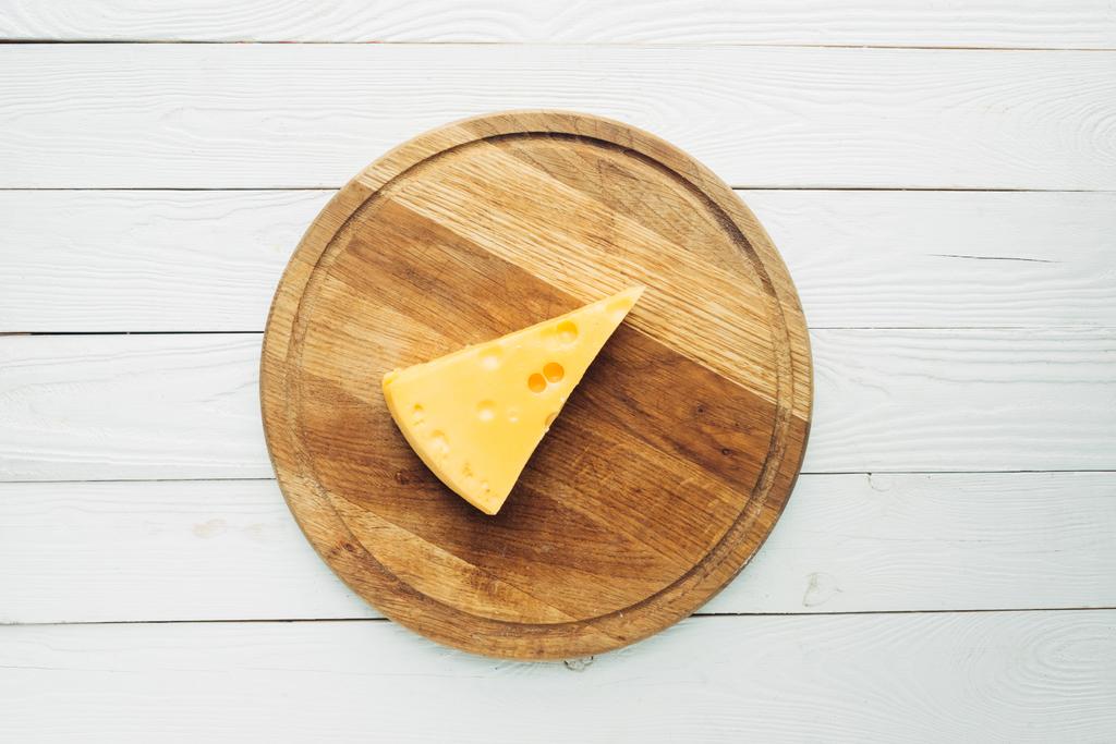 stukje kaas op snijplank - Foto, afbeelding