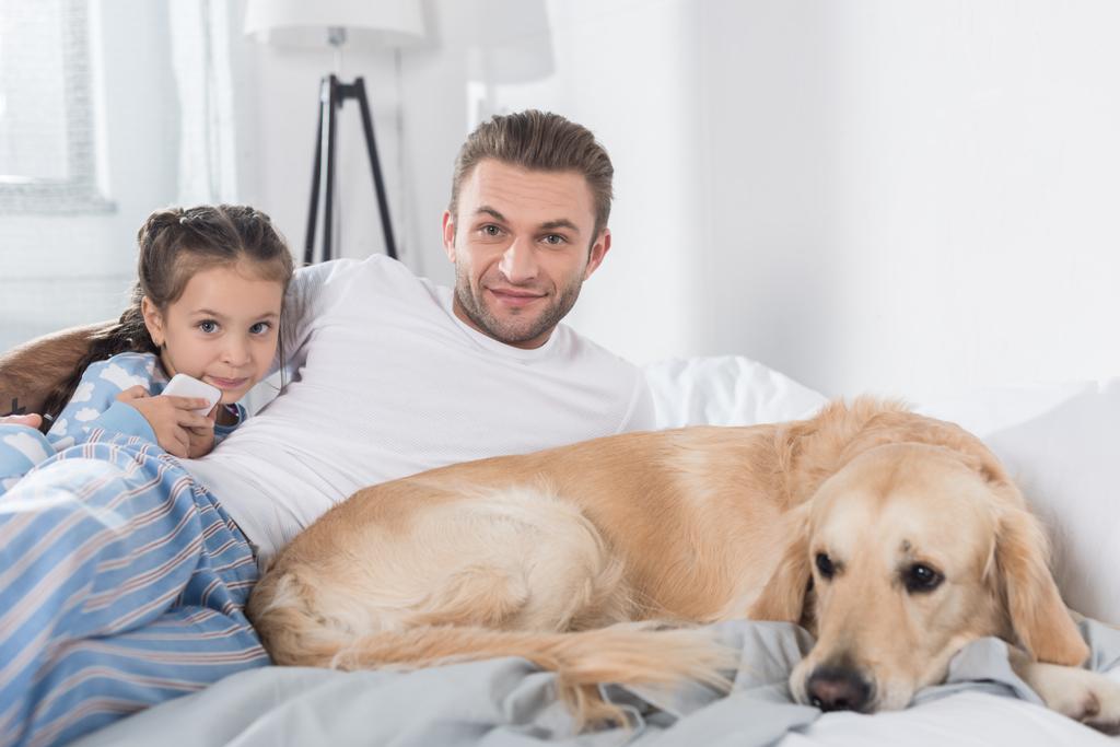 Père et fille avec chien au lit
 - Photo, image