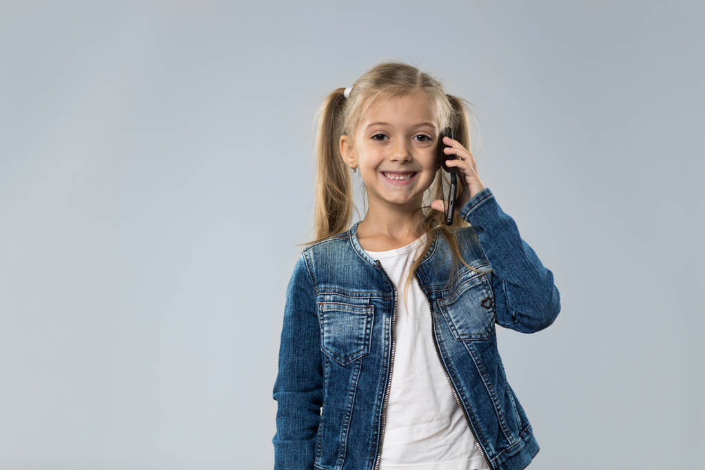 Маленькая девочка говорит по телефону смартфон, маленький ребенок счастливый улыбающийся ребенок
 - Фото, изображение