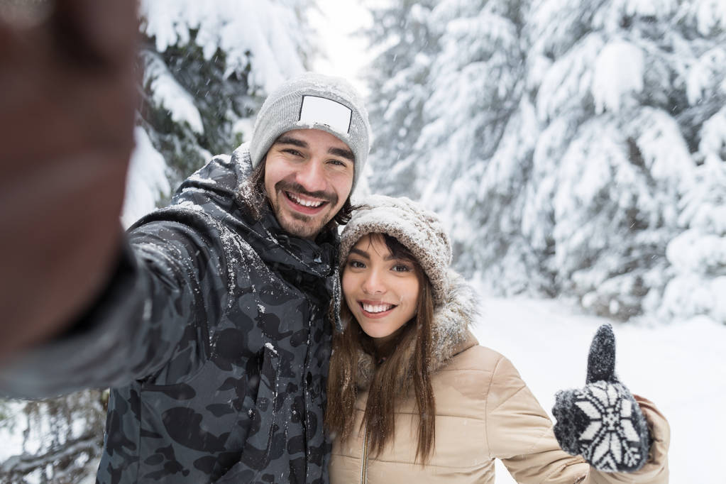 Hombre tomando foto selfie joven pareja romántica sonrisa nieve bosque al aire libre
 - Foto, Imagen