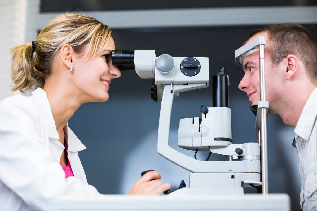 Concepto de optometría: joven guapo que examina sus ojos
 - Foto, Imagen