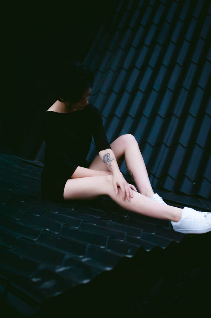 beyaz spor ayakkabı ve kentsel manzara fonunda siyah elbise giymiş güzel ayaklı genç kadın - Fotoğraf, Görsel