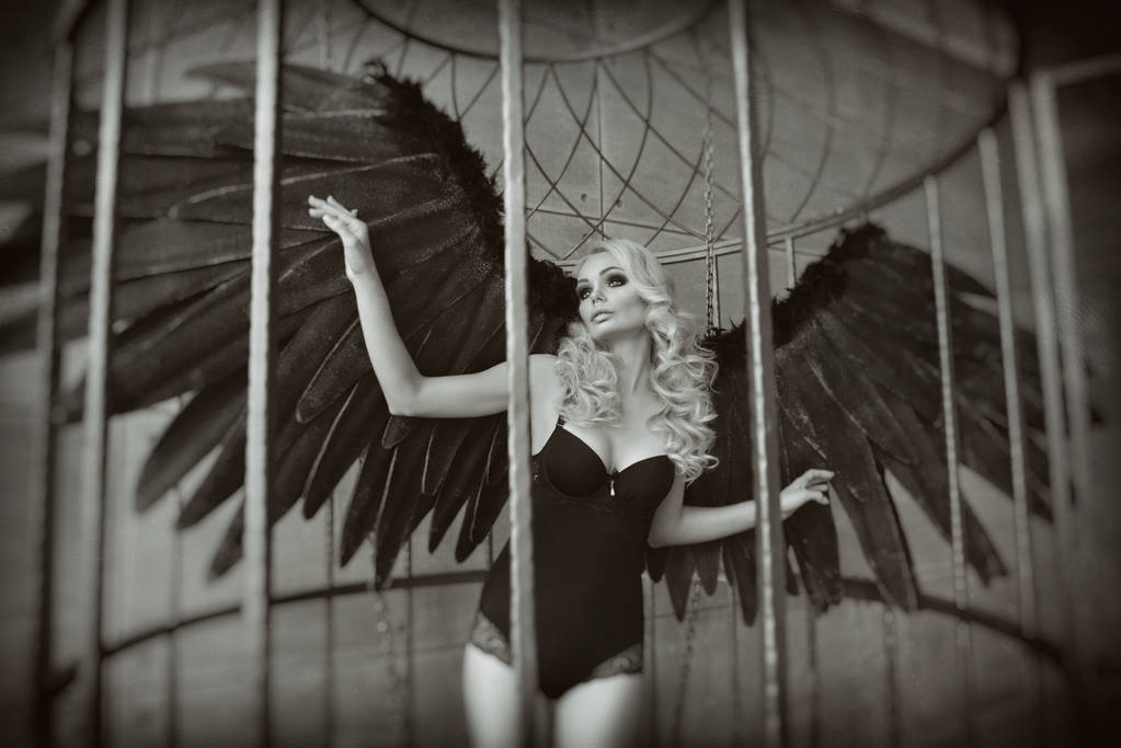 mulher loira com asas pretas em uma jaula. Anjo, misticismo
 - Foto, Imagem