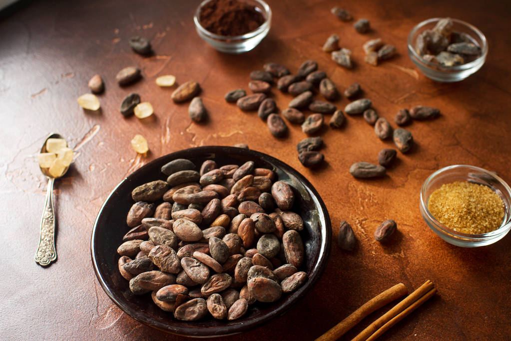 Сирі боби какао, порошок какао та коричневий цукор на фоні темного каменю
 - Фото, зображення