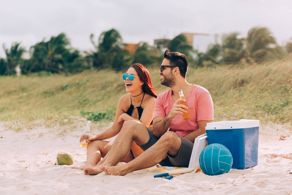 Ζευγάρι πίνοντας μπύρα και έχοντας διασκέδαση στην παραλία - Φωτογραφία, εικόνα