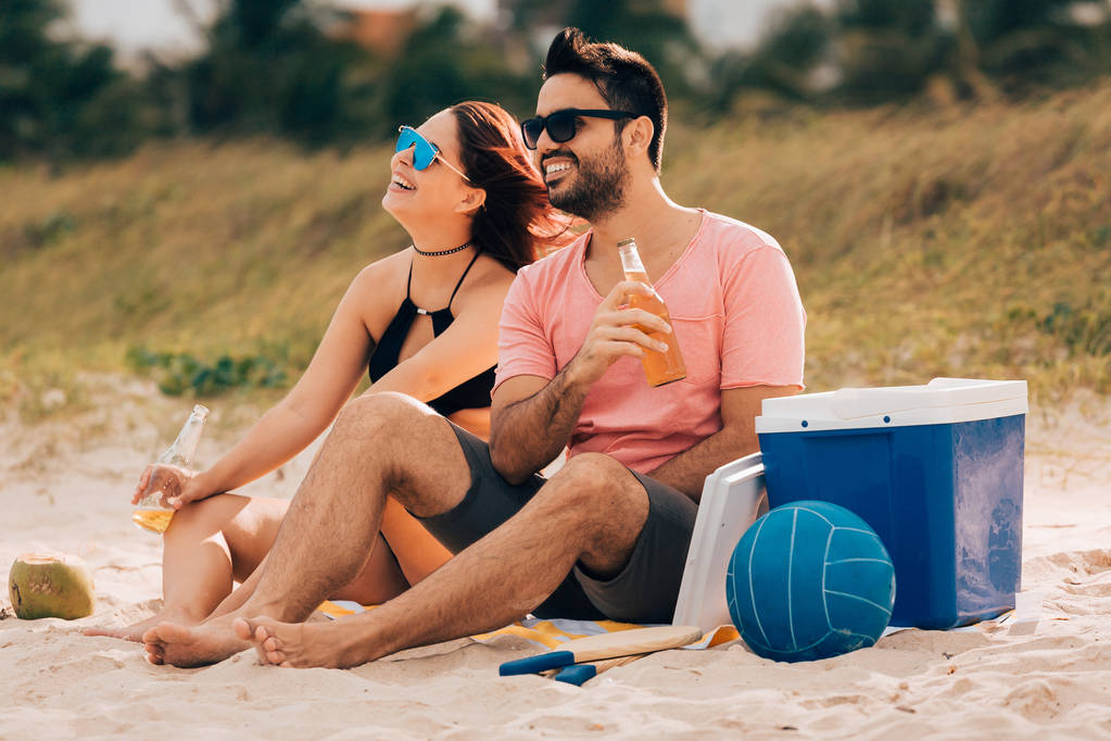 Пара п'є пиво і розважається на пляжі
 - Фото, зображення