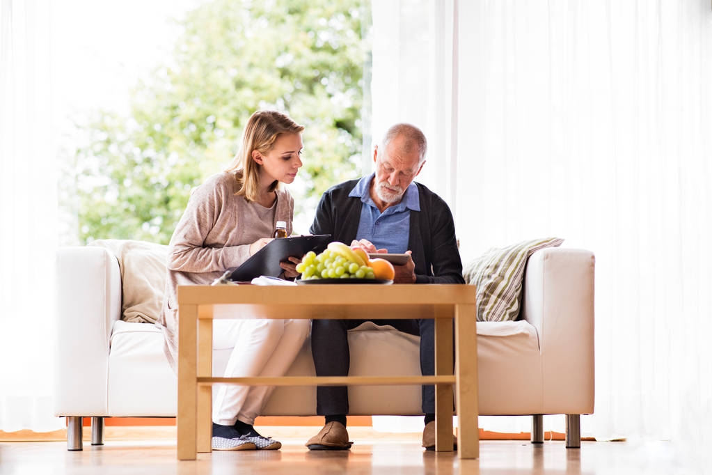 Visitante de saúde e um idoso com tablet durante visita domiciliar
. - Foto, Imagem