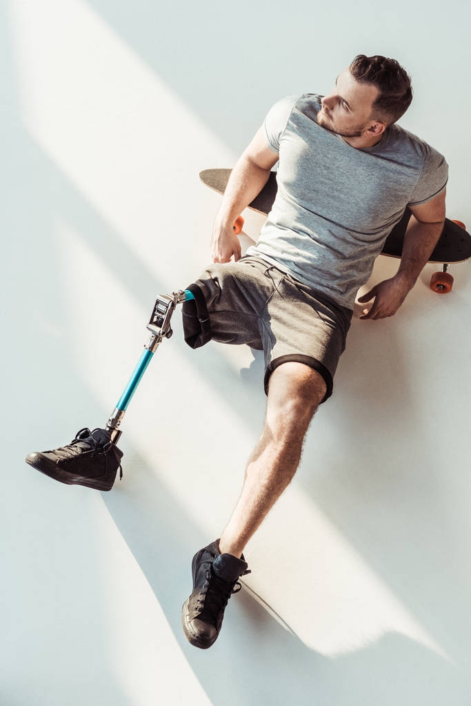 man met been prothese rust op het skateboarden - Foto, afbeelding