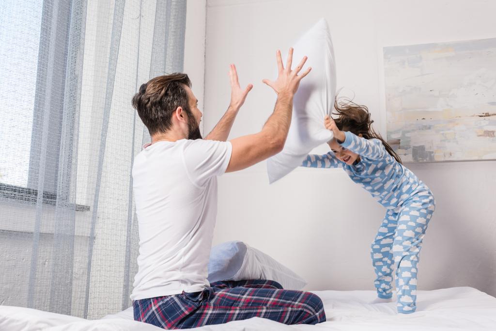 Отец и дочь играют в битву подушками
 - Фото, изображение