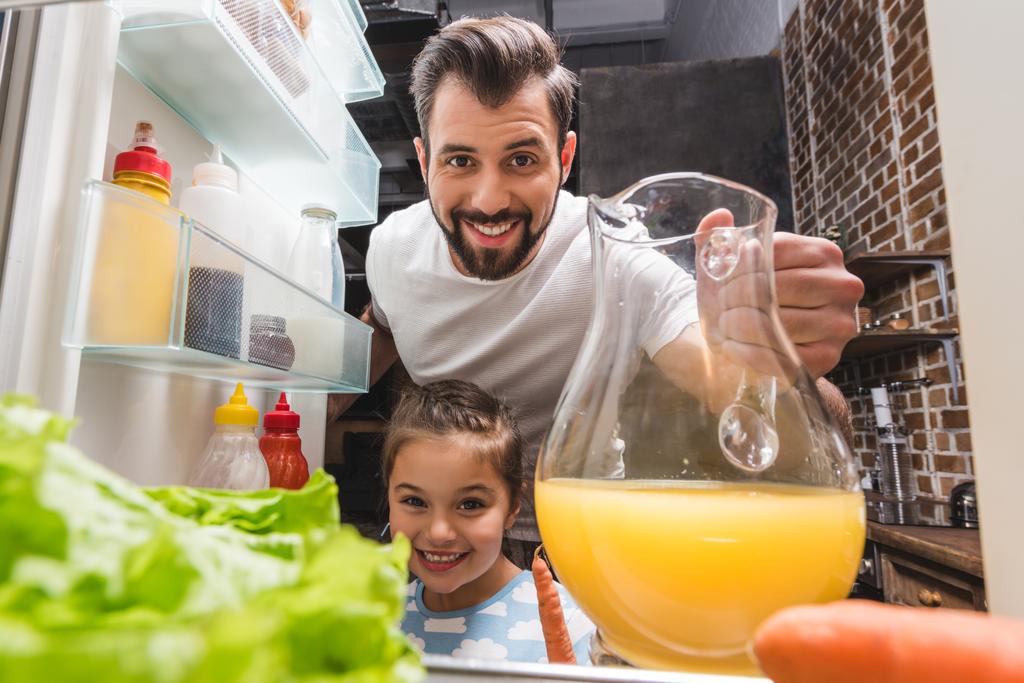 father and daughter taking juice from fridge - Photo, Image