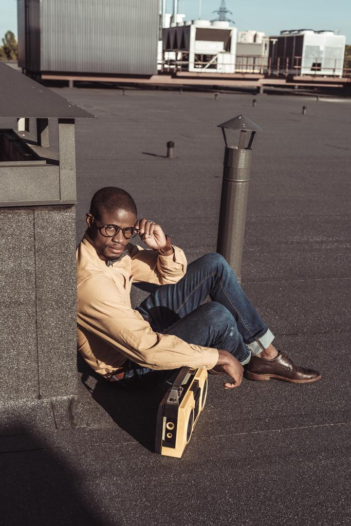 Αφρικανική αμερικανική άνθρωπος που κάθεται στον τελευταίο όροφο με boombox - Φωτογραφία, εικόνα