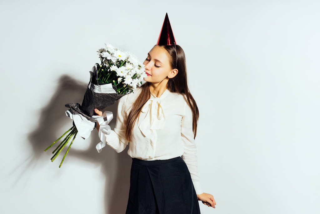 une fille dans un chapeau de fête jouit de l'odeur des fleurs
 - Photo, image