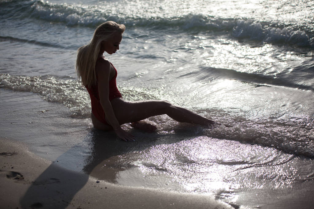Сексуальна дівчина лежить у червоному купальнику біля океану. Вид ззаду
. - Фото, зображення