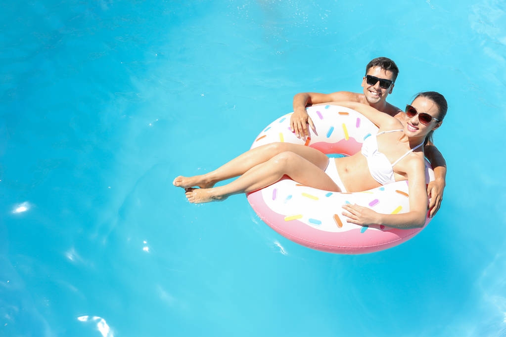 Felice giovane coppia con ciambella gonfiabile in piscina
 - Foto, immagini