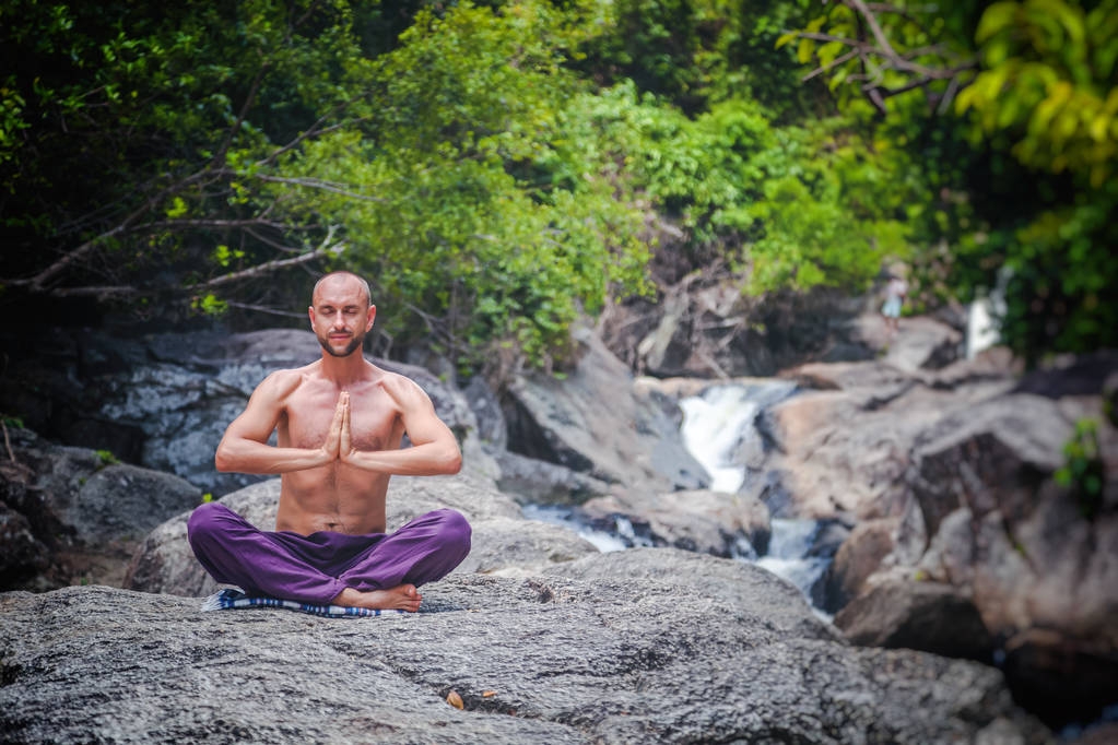 Un joven atractivo se sienta en una pose de loto y medita de nuevo
 - Foto, Imagen