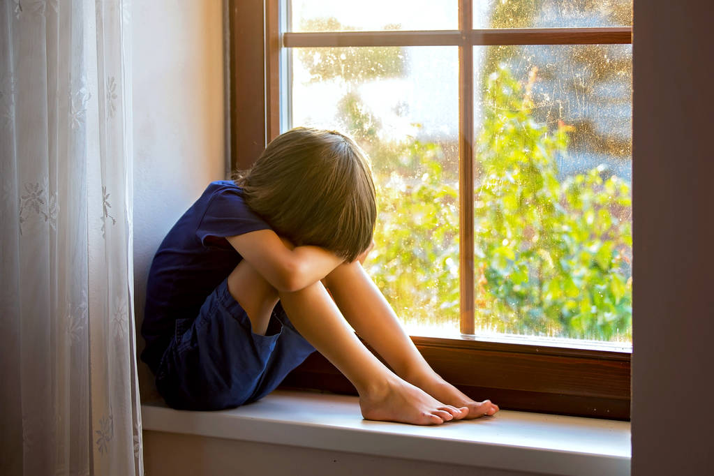 Niño triste, muchacho, sentado en un escudo de ventana
 - Foto, imagen