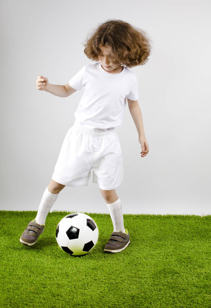 Joven futbolista jugando al fútbol en el césped. Fondo gris
. - Foto, imagen