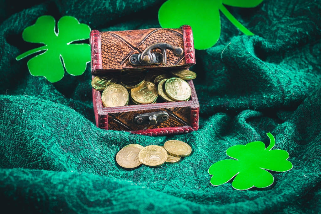 eine Truhe mit Goldmünzen auf grünem Hintergrund. Kleeblätter. St. Patrick 's Day. - Foto, Bild