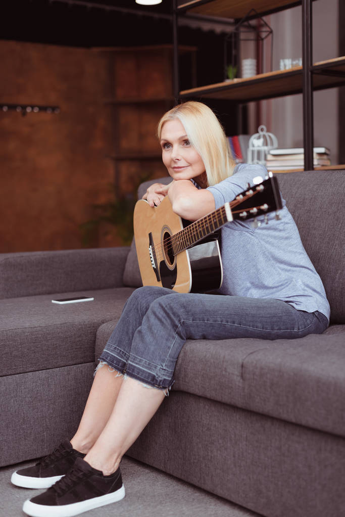 Frau mittleren Alters mit Gitarre zu Hause - Foto, Bild
