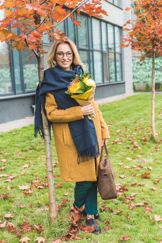 mujer con estilo con flores en el parque de otoño
 - Foto, Imagen