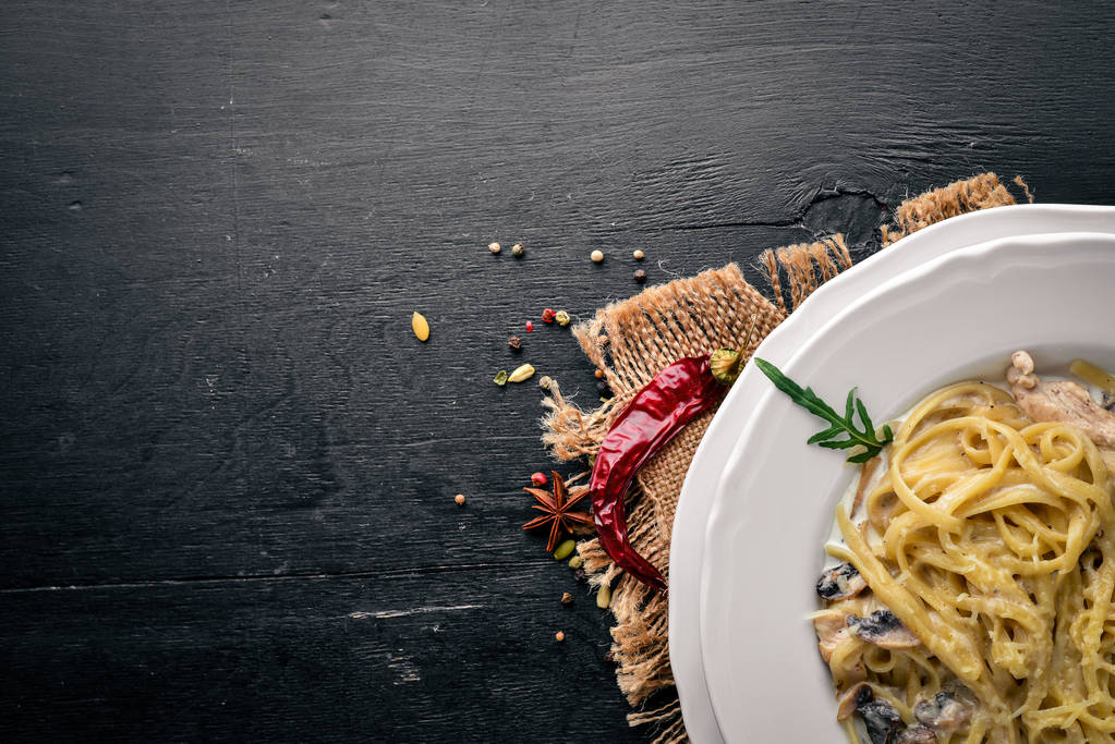 チキンとキノコのパスタ。イタリア料理。木製の背景。平面図です。テキスト用の空き容量. - 写真・画像