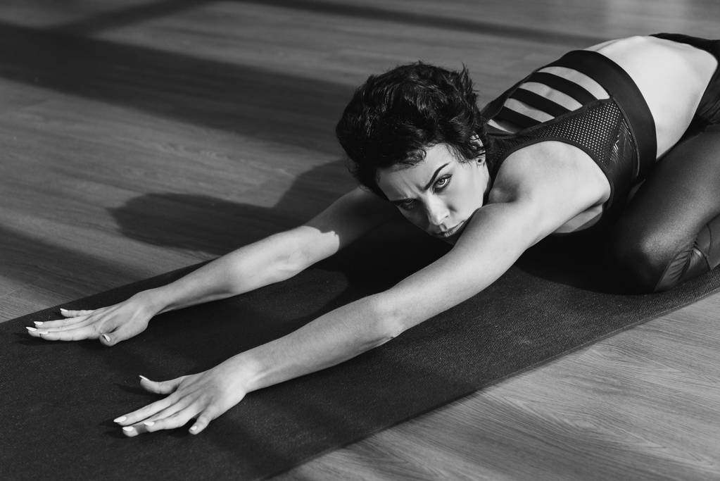 Женщина растягивается на коврике для йоги
 - Фото, изображение