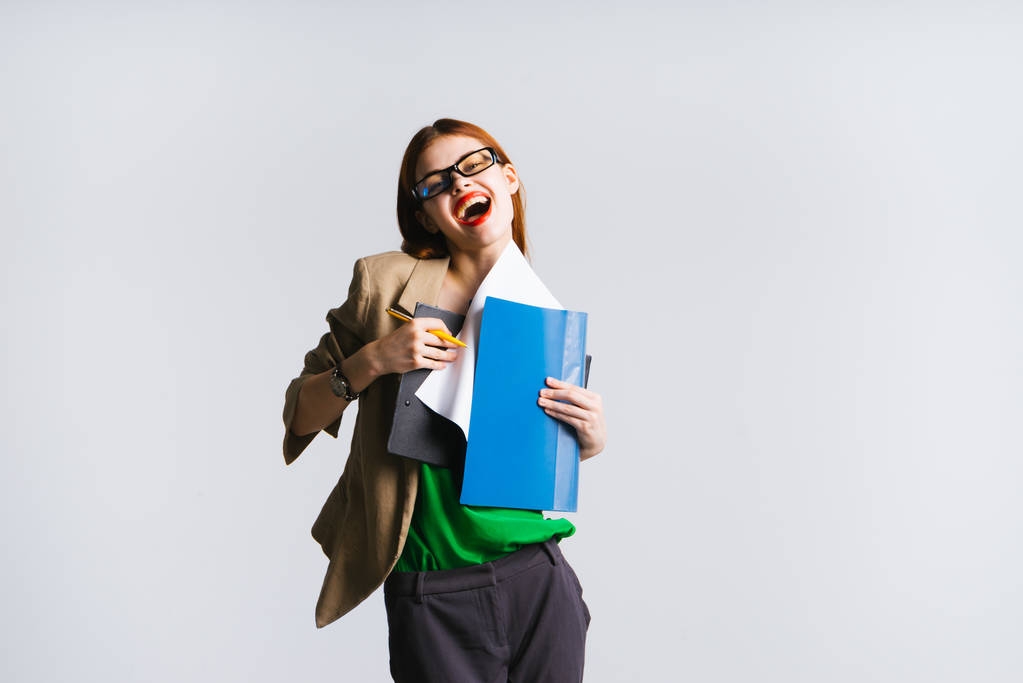 gelukkig lachen roodharige meisje met bril houdt documenten mappen - Foto, afbeelding