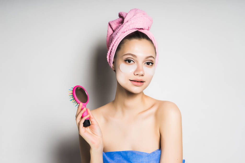 beautiful girl with clean skin and with a pink towel on her head holds a comb - Photo, Image