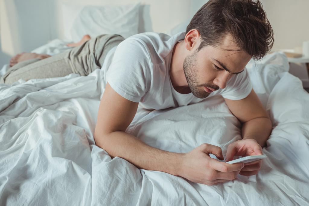 Ο άνθρωπος που χρησιμοποιεί Smartphone στο κρεβάτι - Φωτογραφία, εικόνα