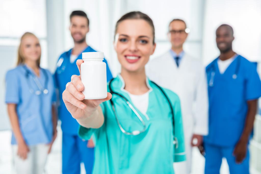 медсестра показує банку таблеток
 - Фото, зображення