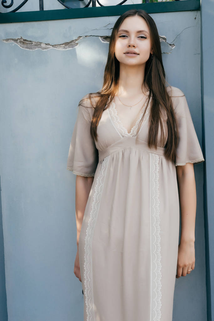 belle fille charmante en robe beige posant contre le mur, souriant
 - Photo, image