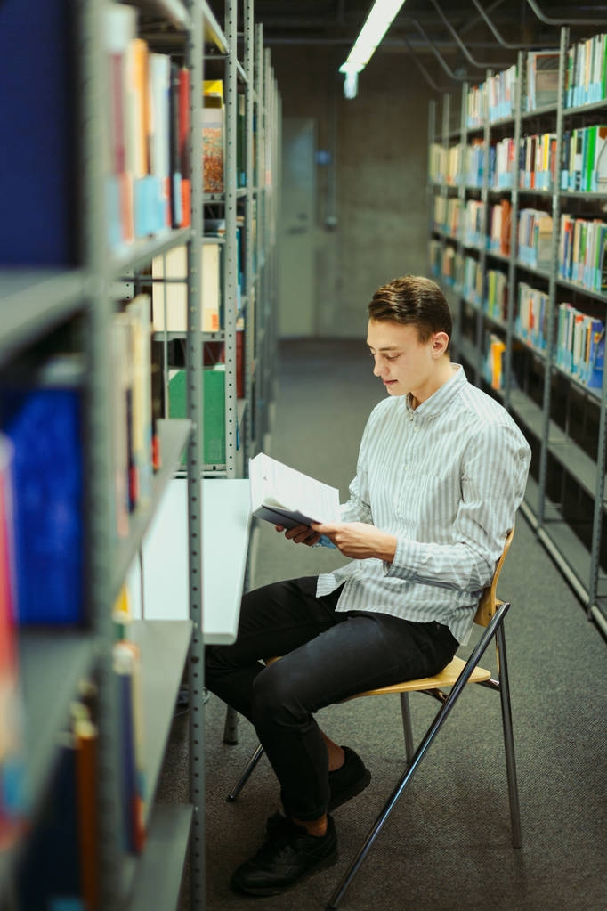 Homem sentar na biblioteca e ler livro com fundo desfocado
 - Foto, Imagem