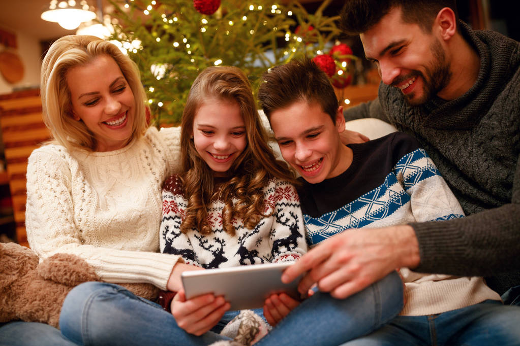 familia sonriente divertirse en la tableta digital para Navidad
 - Foto, imagen