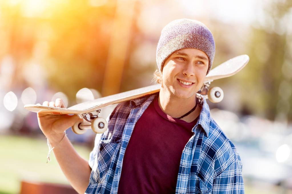 Tiener met skateboard permanent buitenshuis - Foto, afbeelding
