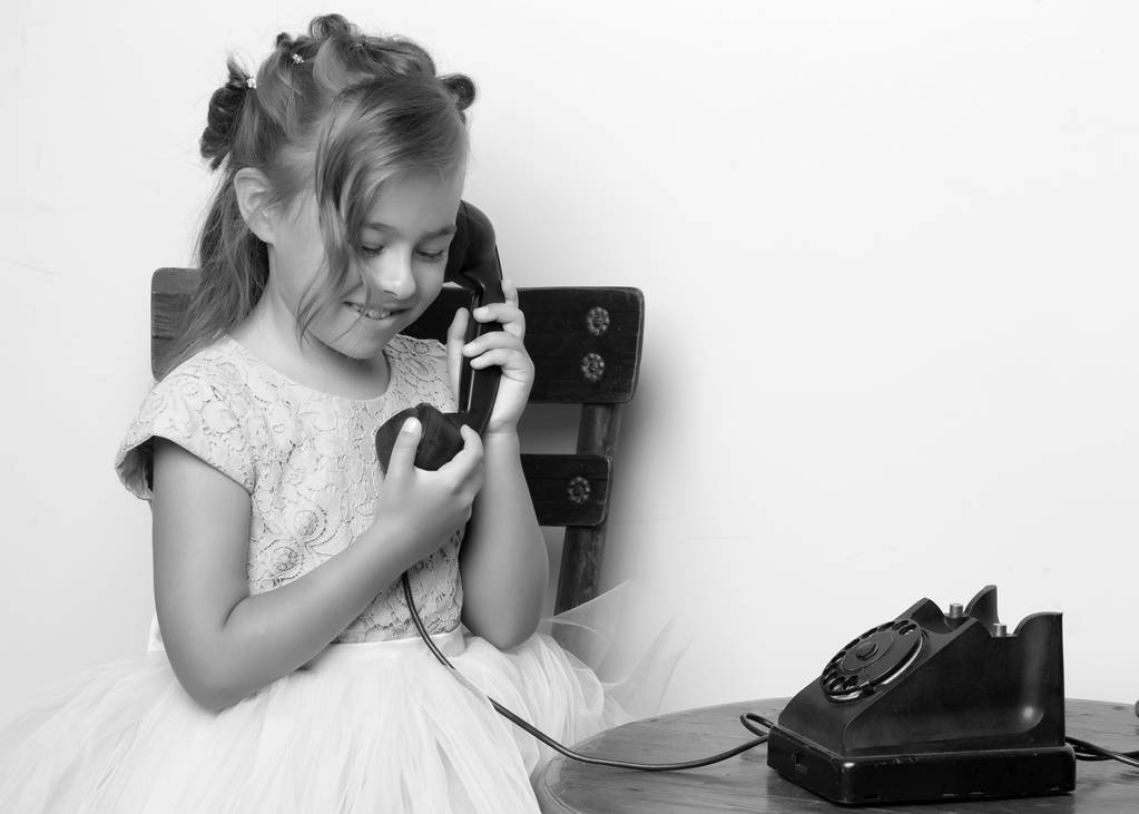 Uma menina está tocando no telefone antigo. - Foto, Imagem