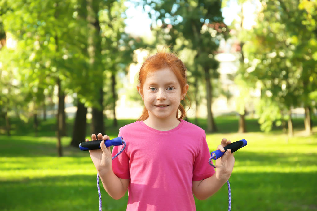 Симпатична маленька дівчинка зі стрибками мотузкою в парку
 - Фото, зображення