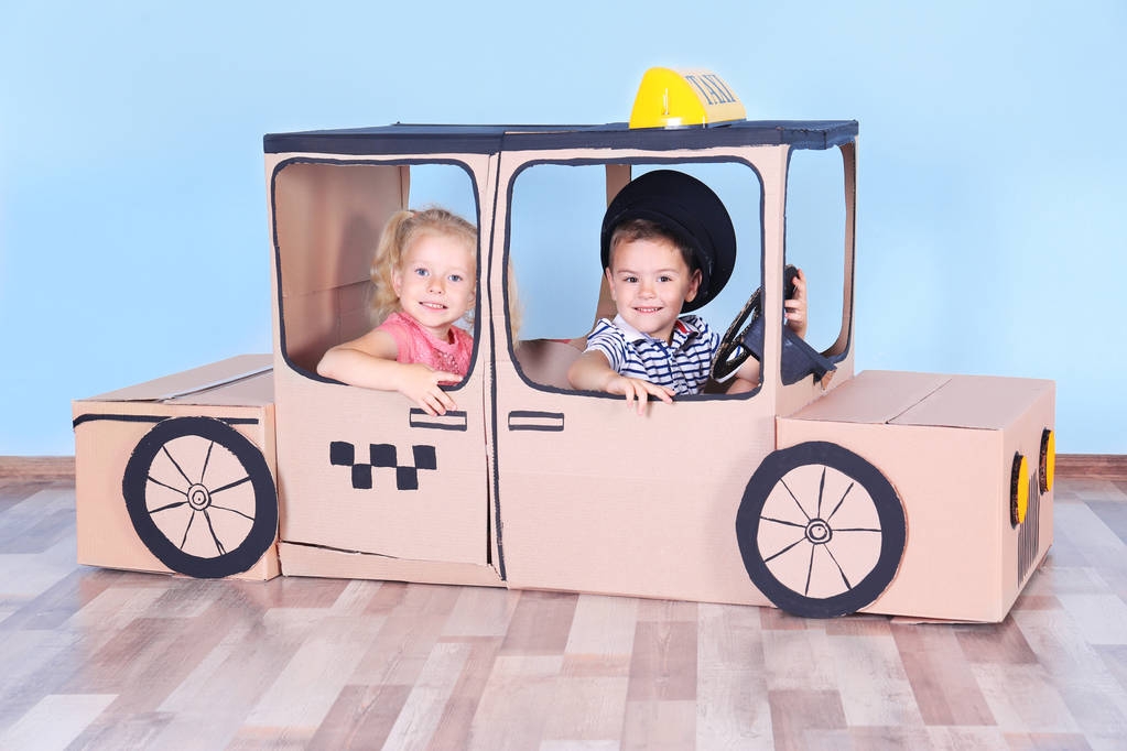 Małe dzieci bawiące się z tektury taxi w pokoju światło - Zdjęcie, obraz