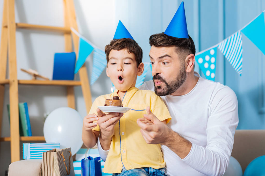 Веселий син і тато вибухають свічки на день народження торта
 - Фото, зображення