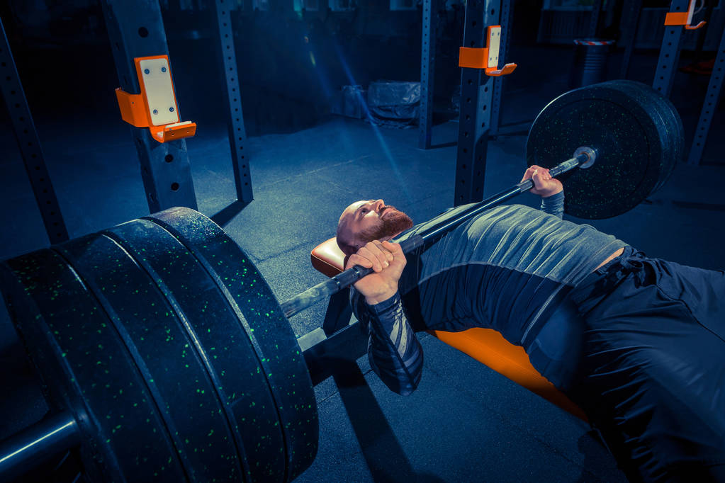 Retrato de un joven musculoso súper en forma haciendo ejercicio en el gimnasio con barra
 - Foto, imagen