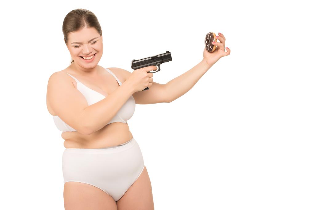 ylipainoinen nainen ase ja donitsi
 - Valokuva, kuva