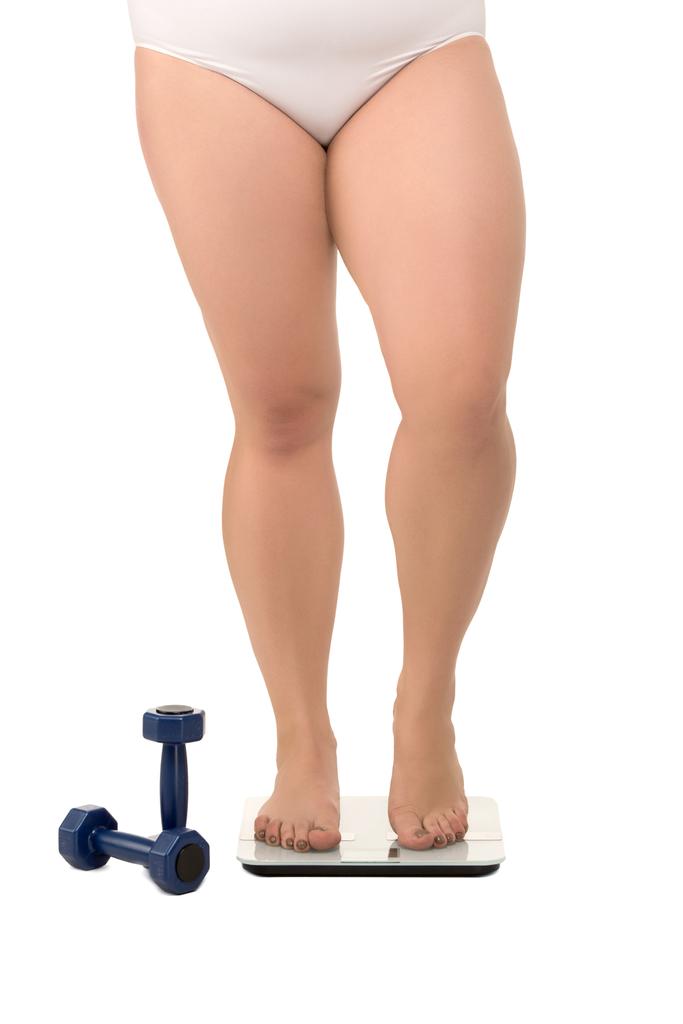 Толстая женщина на весах рядом с гантелями
 - Фото, изображение