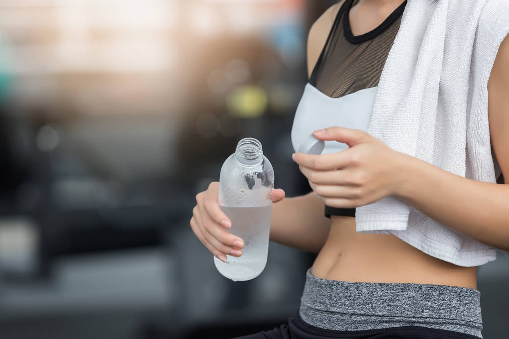 Fitnessfrau trinkt nach dem Training im Fitnesssportclub Wasser aus der Flasche - Foto, Bild